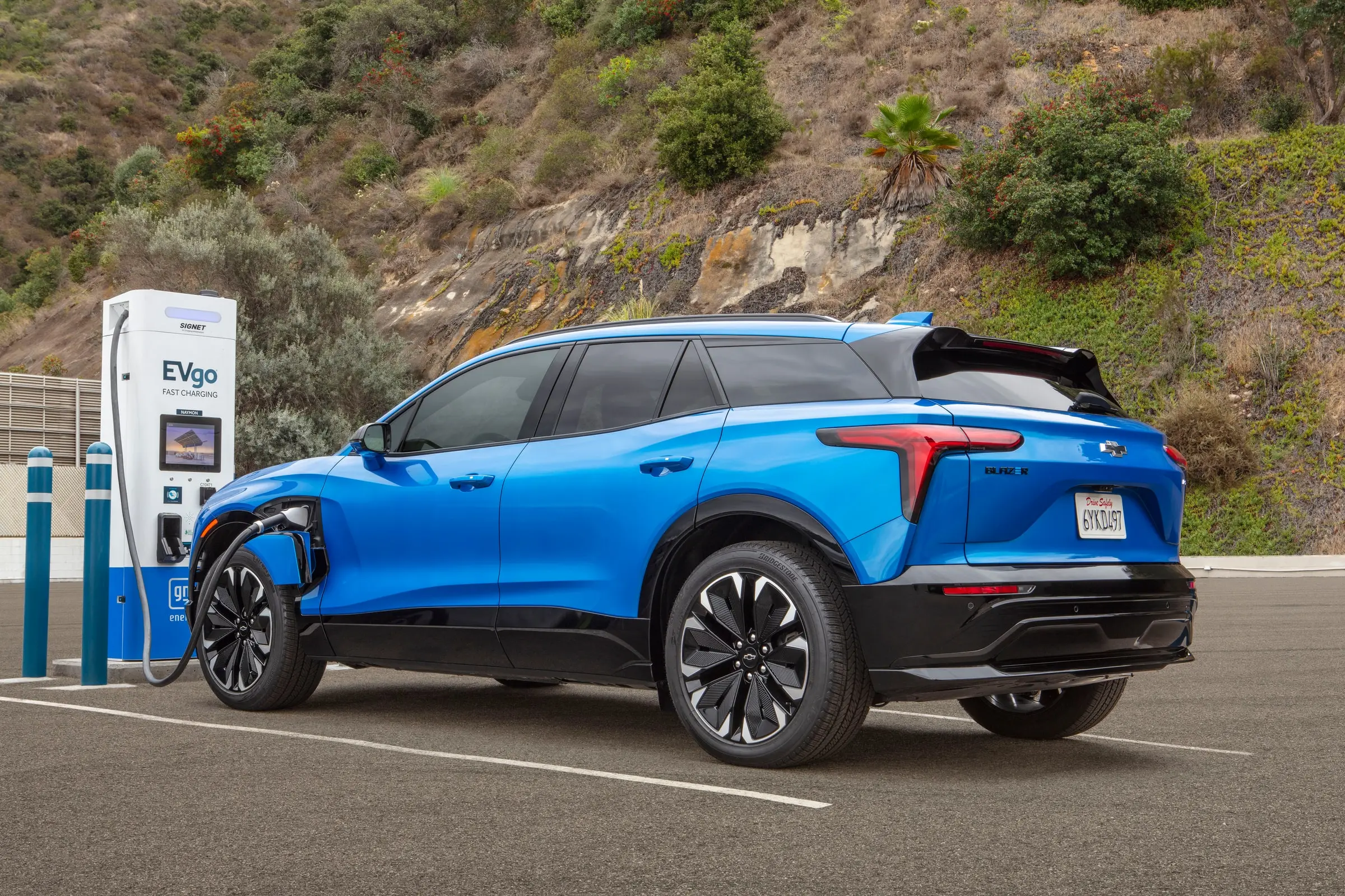A blue Chevrolet Blazer EV plugged in at a public fast charger