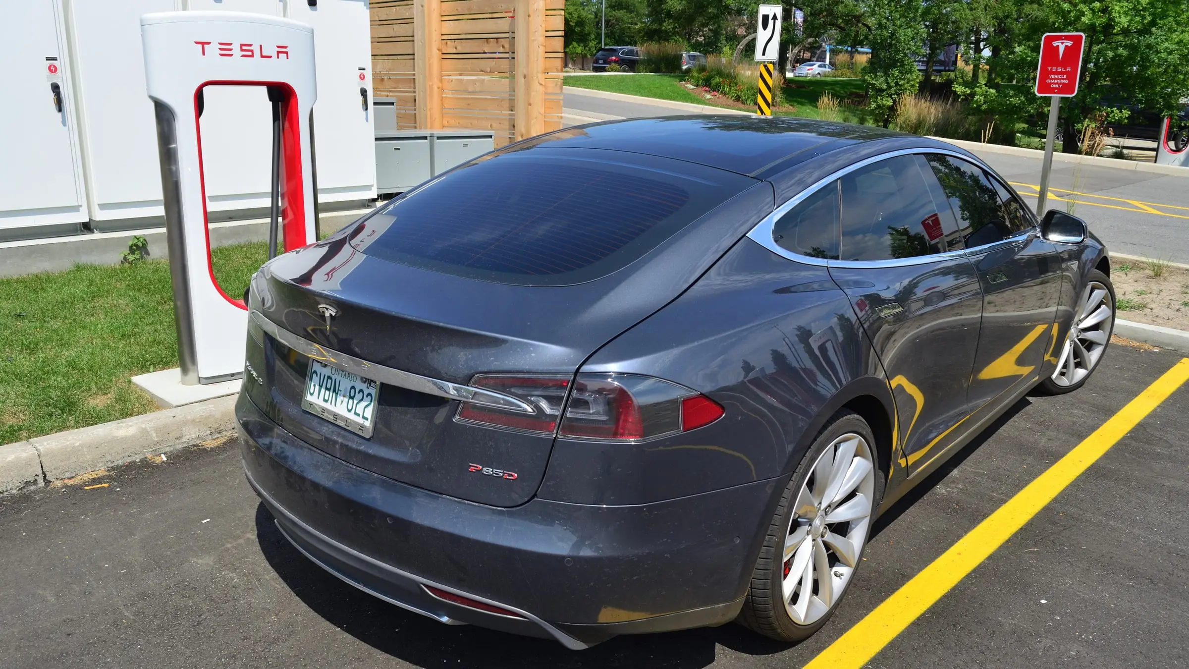 A dark grey Tesla Model S P85D parked at a Tesla Supercharger in Markham, Ontario, seen from the rear three-quarter
